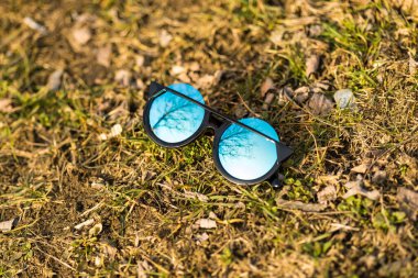 Özel tasarımı olan bayanlar için büyük mavi lensleri olan güneş gözlüklü özel bir model doğada yakın çekim yapıyor. Seçici odak 