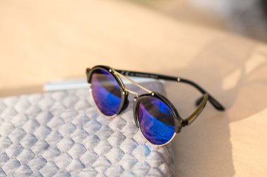 Mavi yuvarlak lensli Retro güneş gözlüğü modeli bir yaz günü yakın plan çekimde dışarıda çekiliyor. Seçici odak