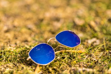 Mavi lensli klasik güneş gözlüğü modeli güneşli bir günde dışarıda çekim yapıyor. Seçici odak