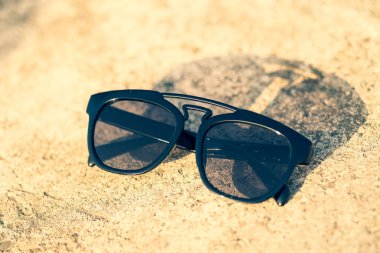 Güneşli bir günde siyah lensli ve siyah çerçeveli güneş gözlükleri dışarıda çekiliyor. Seçici odak