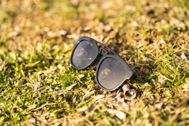Güneşli bir günde siyah lensli ve siyah çerçeveli güneş gözlükleri doğanın dışında çekiliyor. Seçici odak