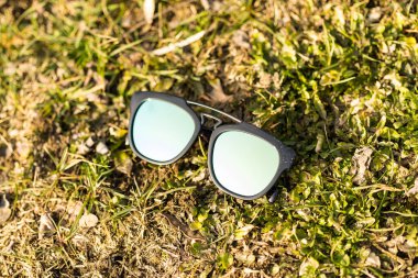 Güneşli bir günde çimlerin üzerinde mavi lensli güneş gözlüğü modeli çekiliyor. Seçici odak