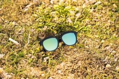 Güneşli bir günde çimlerin üzerinde mavi lensli güneş gözlüğü modeli çekiliyor. Seçici odak