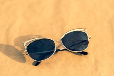 Güneşli bir günde dışarıda siyah lensli ve altın çerçeveli çekim yapan bayanlar için moda kedi gözü güneş gözlüğü modeli. Seçici odak 