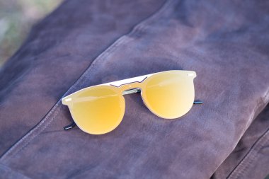 Güneşli bir günde dışarıda altın yuvarlak lensli özel tasarım güneş gözlükleri çekiliyor. Seçici Odaklanma