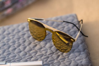 Özel tasarım güneş gözlükleri ve kahverengi yuvarlak lensler bir yaz günü yakın plan çekimde dışarıda çekiliyor. Seçici Odaklanma