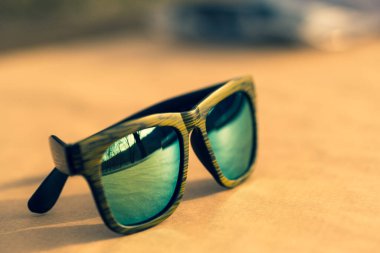 Güneşli bir günde yansıyan lensleri ve yeşil çerçeveli klasik güneş gözlüğü modeli. Seçici odak