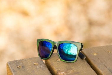 Klasik güneş gözlüğü modeli, mavi yansıtıcı lensler ve yeşil çerçeveli, yaz günü yakın plan. Seçici odak