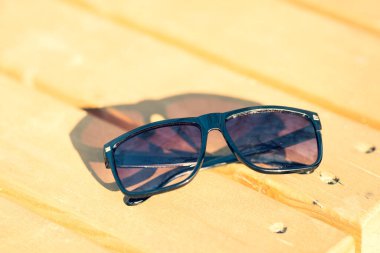 Siyah lensli ve siyah çerçeveli kadınlar ve erkekler için klasik güneş gözlüğü tasarımı. Kapanış yazında dışarıda çekilecek. Seçici odak