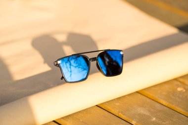 Büyük mavi lensli büyük boy güneş gözlüğü modeli güneşli bir günde dışarıda çekim yapıyor. Seçici odak