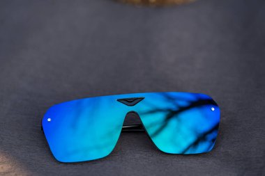 Mavi lensli fütüristik güneş gözlüğü modeli yakın çekim dışında bir yaz gününde güneşi yansıtıyor. Seçici odak 