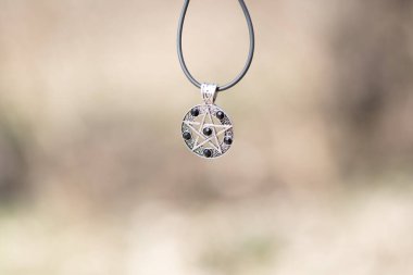 Kolye sihirli pentagram kolye gümüş ve siyah renkli paslanmaz çelik atış Bir yaz günü kapalı. 