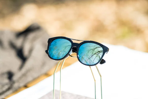 Дизайн модних сонцезахисних окулярів з синіми лінзами знімається на вулиці в літній день крупним планом. Вибірковий фокус — стокове фото