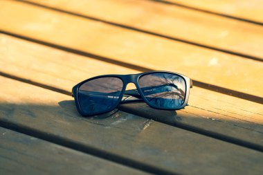 Güneşli bir günde dışarıda siyah lensli ve siyah çerçeveli klasik güneş gözlüğü tasarımı. Seçici odak