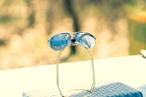 Модель в солнечных очках с большими серебряными линзами снимается на улице в солнечный день крупным планом. Селективный фокус — стоковое фото