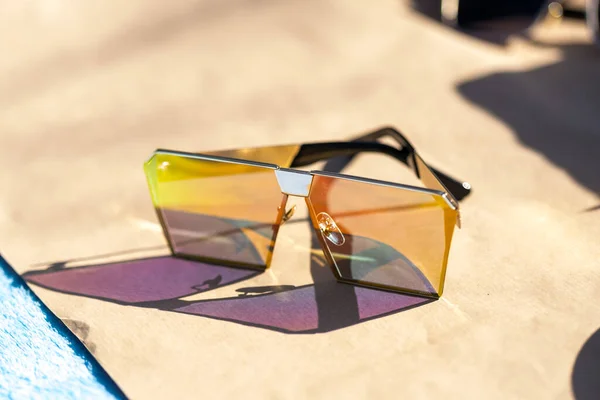 Модель негабаритних сонцезахисних окулярів з великими плоскими лінзами знімається на вулиці в сонячний день крупним планом. Вибірковий фокус — стокове фото