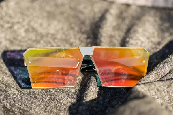 Zróżnicowany model okularów przeciwsłonecznych z dużymi płaskimi soczewkami kręci się na zewnątrz w słoneczny dzień zbliżenia. Skupienie selektywne — Zdjęcie stockowe