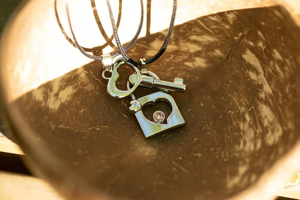 Couple set pendant necklace with a key and a lock for lovers shoot outdoors in a sunny day closeup. Selective focus