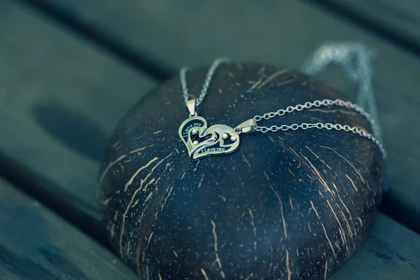 Couple set pendant necklace two half of a heart shoot outdoors in a sunny day closeup. Selective focus