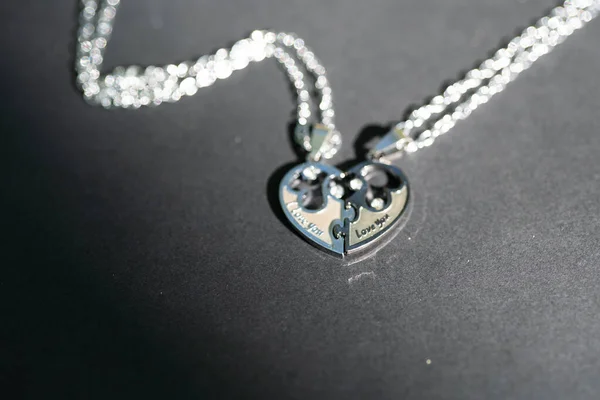 Couple set pendant necklace two half of a heart shoot outdoors in a sunny day closeup. Selective focus — Stock Photo, Image