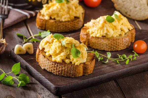 Huevos revueltos con hierbas y ajo sobre pan tostado —  Fotos de Stock