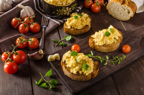 Scrambled eggs with herbs and garlic on toasted bread — Stock Photo, Image