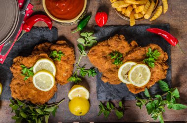 Schnitzel with fries, salad and herbs clipart