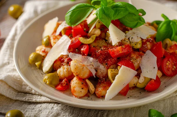 Delicious and simple food, homemade gnocchi with tomato sauce, parmesan, olives and basil
