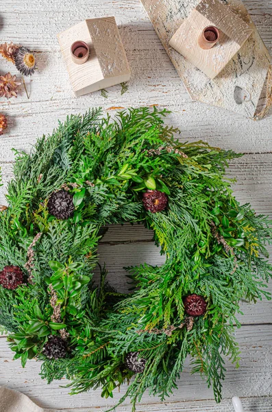 Noel tatili için ev yapımı ahşap evlerle doğal çelenk.