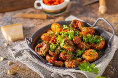 Kızarmış mantar ve bitkilerle kaplı kırmızı biber sosu.