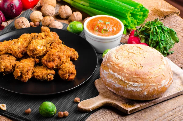 Spicy breaded chicken wings with homemade bread — Stock Photo, Image