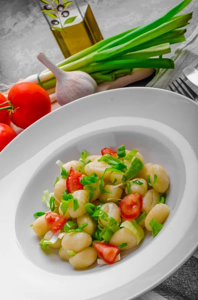 Vegetarian gnocchi with spring onions and tomatoes — Stock Photo, Image