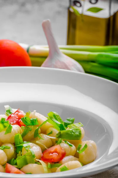 Vegetarian gnocchi with spring onions and tomatoes — Stock Photo, Image