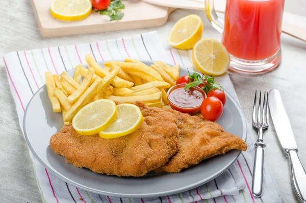 Schnitzel com batatas fritas e um molho picante — Fotografia de Stock