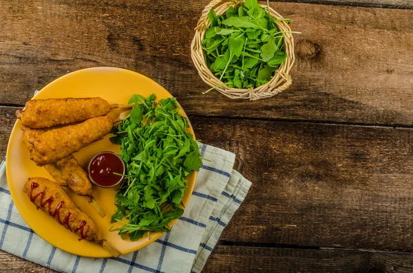 Perro de maíz con ensalada de rúcula fresca y salsa caliente —  Fotos de Stock