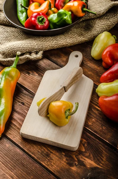 Slicing peppers with wood knife — Stock Photo, Image