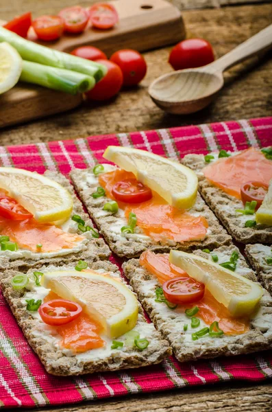 Bio gezonde voeding - kneckebrot verspreid kaas met gerookte zalm en cherry tomaten — Stockfoto