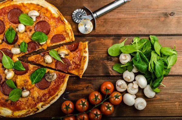Rustieke pizza salami, mozzarella en spinazie — Stockfoto