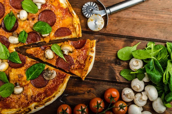 Rustieke pizza salami, mozzarella en spinazie — Stockfoto