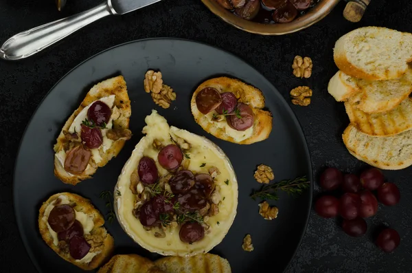 Brie cheese baked with nuts and grapes — Stock Photo, Image