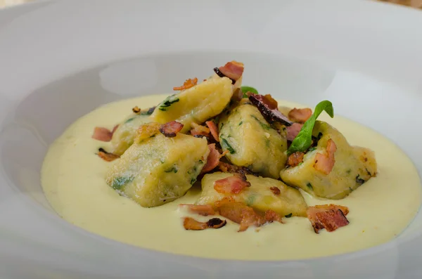 Spinach gnocchi with parmesan sauce topped with bacon — Stock Photo, Image