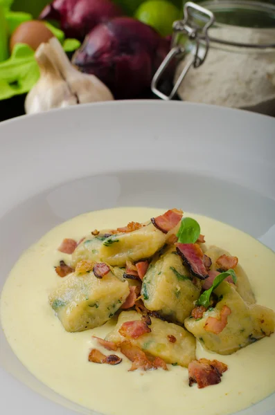 Spinach gnocchi with parmesan sauce topped with bacon — Stock Photo, Image