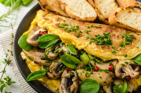 Omelet with mushrooms, lambs lettuce, herbs and chilli — Stock Photo, Image