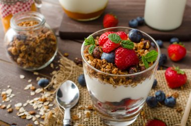 Yogurt with baked granola and berries in small glass clipart