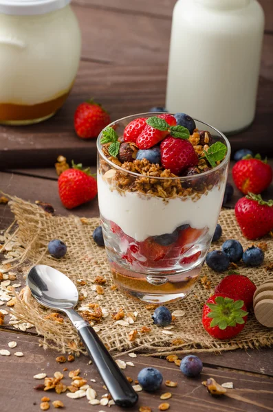 Йогурт з запеченою гранолою та ягодами у маленькому склі — стокове фото
