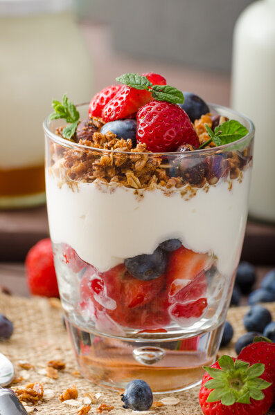 Yogurt with baked granola and berries in small glass