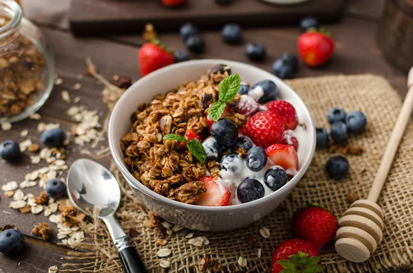 Yogurt with baked granola and berries in small bowl