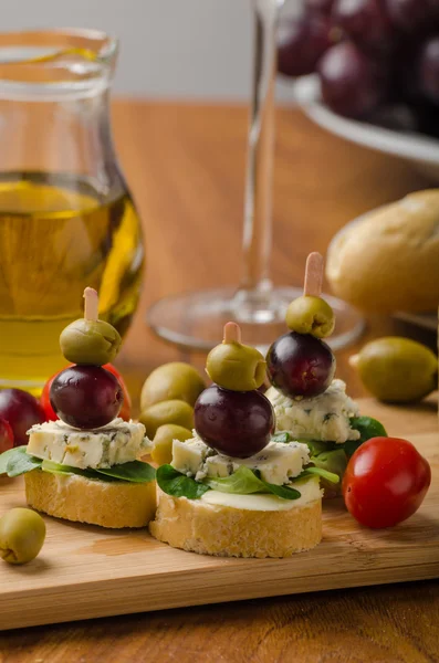 Delicious blue cheese with olives, grapes and salad — Stock Photo, Image