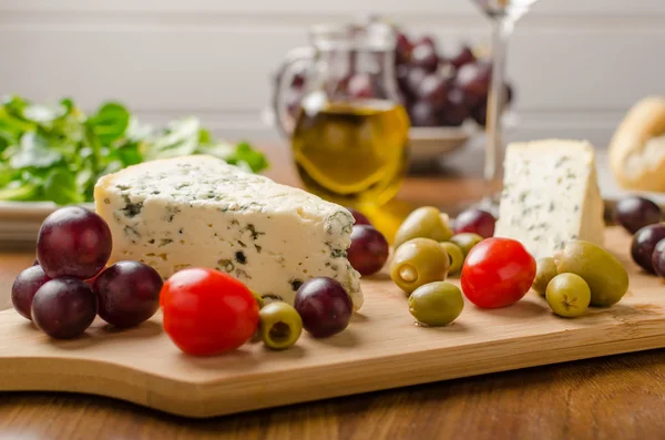 Delicious blue cheese with olives, grapes and salad — Stock Photo, Image