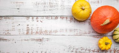 Tahta bir masada farklı renklerde bir kaç olgun balkabağı.